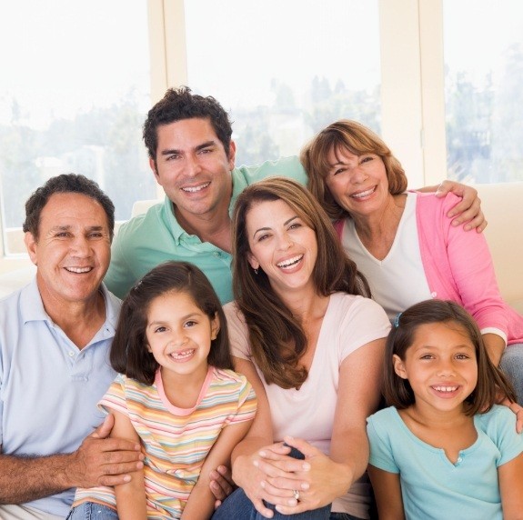 Three generations of smiling family sitting on couch