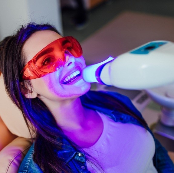 Woman getting professional teeth whitening in dental chair