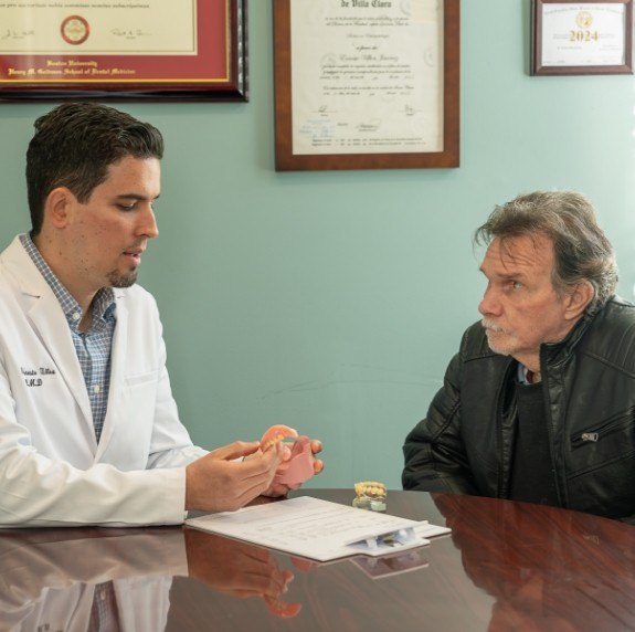 Doctor Ulloa showing a patient a denture