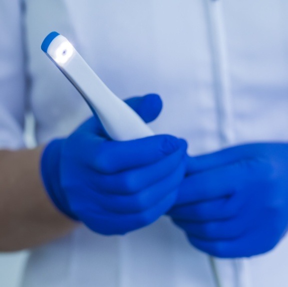 Gloved hands holding a thin white intraoral camera