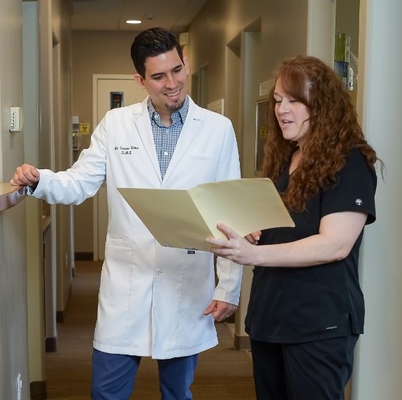 Dental team member showing dentist a file while standing in hallway