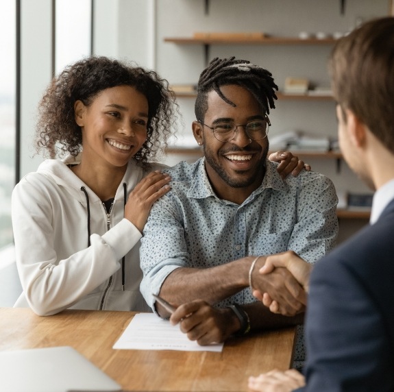 Smiling man shaking hands with person across desk