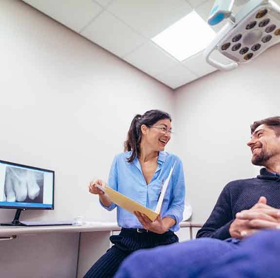 Smiling dentist talking to patient in treatment chair