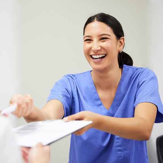 Dental assistant smiling while handing patient form