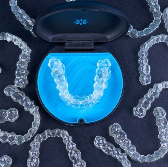 Several Invisalign aligners on table with one set in their carrying case