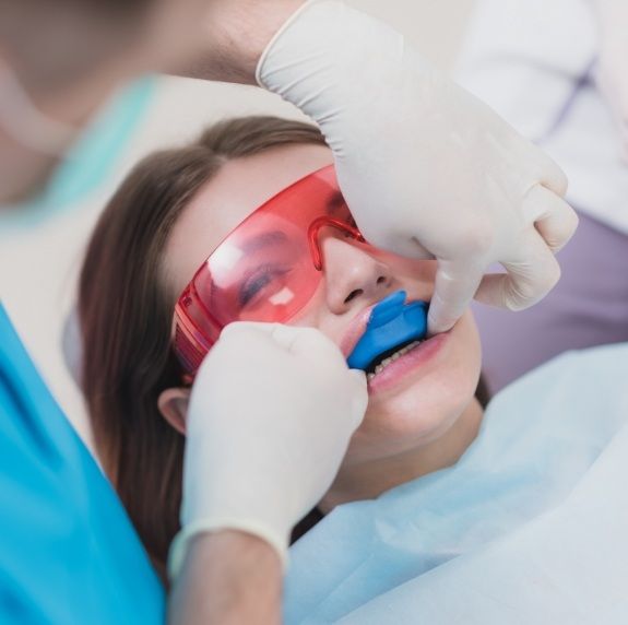 Young woman in dental chair with fluoride trays on her teeth