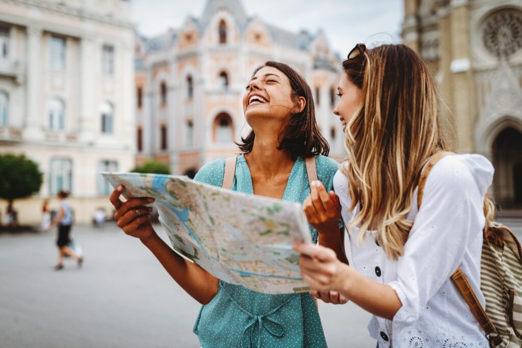 Two friends smiling while looking at map in town square